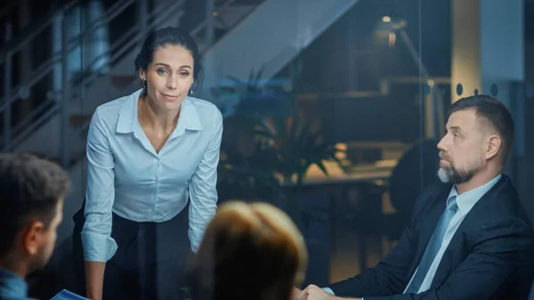 Sala de reuniones corporativas: Directora ejecutiva confiada y hermosa se apoya decisivamente en la mesa de conferencias y entrega informe a una junta de ejecutivos sobre los ingresos récord de la compañía — Foto de Stock