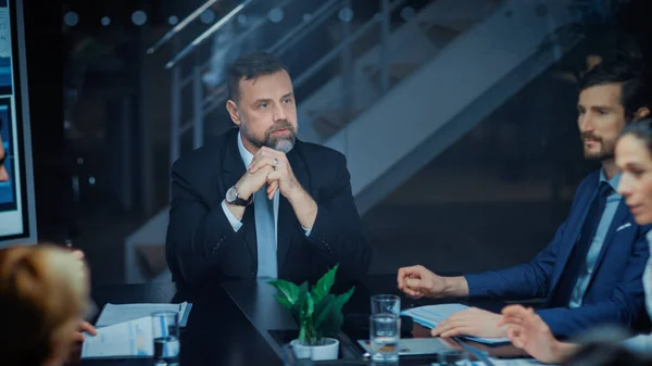 Corporate Meeting Room: Charismatic Director Decisively Leans on a Conference Table and Delivers Report to a Board of Executives about Company s Record Breaking Revenue