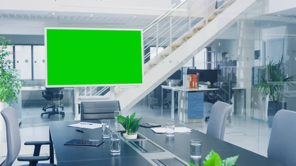 En la sala de reuniones de la oficina corporativa destaca el televisor de pantalla simulada verde o la pizarra digital interactiva en modo horizontal. En el fondo Gran oficina ocupada brillante — Foto de Stock