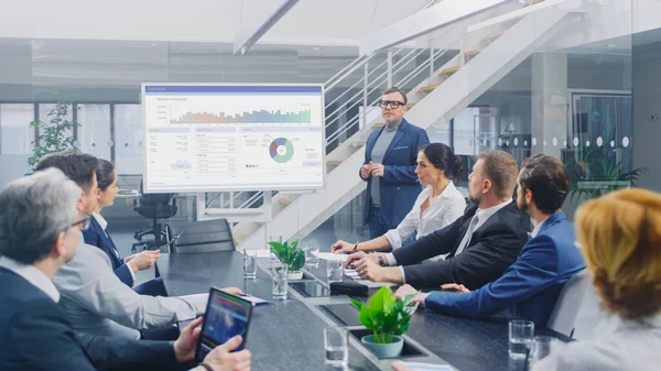 Vállalati tárgyalóteremben: A kreatív igazgató digitális interaktív táblát használ a Vezetőtanács, az ügyvédek, a befektetők és az üzletemberek számára történő bemutatáshoz. Vetítővászon mutatja vállalati növekedési adatok — Stock Fotó