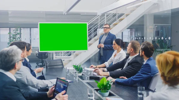 В корпоративном зале заседаний: креативный директор использует цифровую хрому Key Interactive Whiteboard для презентации Совету управляющих, юристов, инвесторов. Зеленый экран макета в горизонтальном режиме — стоковое фото