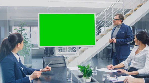 В корпоративном зале заседаний: креативный директор использует цифровую хрому Key Interactive Whiteboard для презентации Совету управляющих, юристов, инвесторов. Зеленый экран макета в горизонтальном режиме — стоковое фото