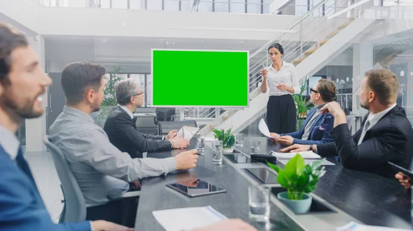 В корпоративном зале заседаний: женщина-спикер использует цифровую хрому Key Interactive Whiteboard для презентации Совету управляющих, юристов, инвесторов. Зеленый экран макета в горизонтальном режиме — стоковое фото