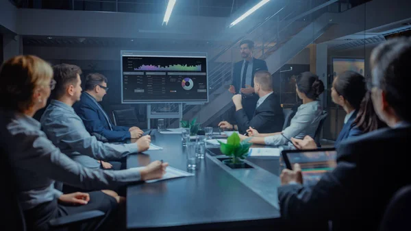 In the Corporate Meeting Room: Male Executive Talks and Use Digital Interactive Whiteboard for Presentation to a Board of Directors, Investors. Na obrazovce jsou zobrazena data růstu. Pozdě v noci kancelář — Stock fotografie