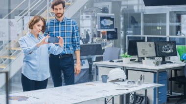 Endüstriyel Mühendislik Tesisinde: Baş Mühendis ile Kadın Tasarımcı, Motor Tasarım Teknik Tasarımlarını 3 boyutlu olarak manipüle etmek için Gelişmiş Gerçeklik Uygulaması Kullanıyor. Yüksek Teknoloji Ofisi. Model