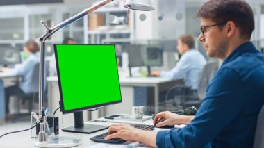 Green Mock-up Masaüstü Bilgisayarı ile çalışan Mühendisin Omuz Çekimi üzerinde. Arkaplan Mühendisliği Tesisi 'nde uzmanlarla Endüstriyel Tasarım ve Planlar üzerinde çalışıyoruz.