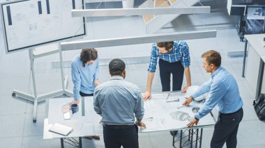 Yoğun Mühendislik Tesisi: Endüstriyel Motor Prototipi Tasarımı üzerine çalışan çeşitli mühendisler, teknisyenler, uzmanlar. Profesyoneller konuşur, çizimler yapar, bilgisayarlar kullanır. Yüksek Açı