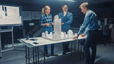 Yaratıcı Mimarlık Ajansı 'nda İki Profesyonel Tasarımcı Şef Proje Mühendisi ile Şehir Bölgesi Modeli Üzerinde Çalışıyor. Şehir Planlayıcıları İşlevsel İnşaat Modeli Üzerinde Çalışıyor.