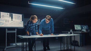 Karanlık Endüstriyel Tasarım Mühendislik Tesisi Erkek ve Kadın Mühendisler Dijital Tablet ve Konferans Masası Kullanarak Bir Planlar Üzerinde Konuşup Çalışıyor. Masaüstü Çizimleri ve Motor Bileşenlerinde