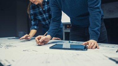 Endüstriyel Tasarım Mühendislik Tesisinde Düşük Açı Çekimi Dijital Tablet ve Konferans Masası Kullanarak Bir Planlar Üzerinde Konuşan ve Çalışan Kadın Mühendisler. Masaüstü Çizimleri Motor Bileşenlerinde