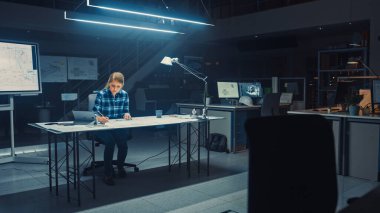 Masasında Oturan Kadın Mühendis Tablet, Cetvel, Cetvel ve Dijital Tablet Kullanarak Tablo Üzerinde Uzanan Planlarla Çalışıyor. Karanlık Endüstriyel Tasarım Mühendislik Tesisinde