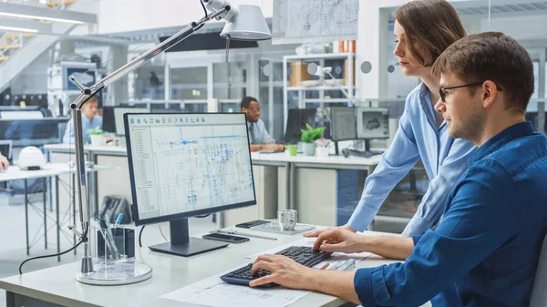 Ingeniero Hablando con Project Manager y Trabajando en Ordenador de Escritorio Usando Software CAD con Dibujos Técnicos en la Pantalla. En la planta de ingeniería de fondo especializada en diseño industrial — Foto de Stock