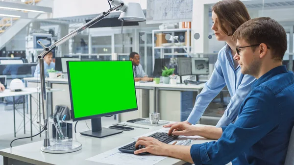 Ingenieur im Gespräch mit Projektmanager und Arbeit mit grünem Mock-up Screen Desktop Computer. Im Hintergrund eine auf Industriedesign spezialisierte technische Einrichtung — Stockfoto