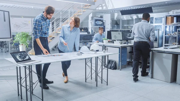 Nel Busy Engineering Facility: Diversi gruppi di ingegneri, tecnici, che lavorano alla progettazione di prototipi di motori industriali. Gli specialisti parlano durante le riunioni, lavorano con i disegni, usano i computer — Foto Stock