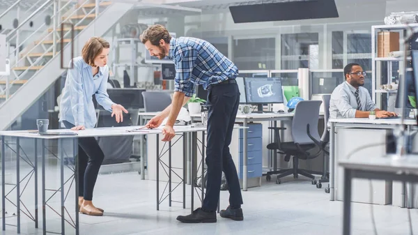 In de Industrial Engineering Facility: Female Architect Prints Concepten van Industrial Engine Prototype en brengt ze naar Chief Engineer, Start Discussie en Analyse met behulp van Conference Table. — Stockfoto