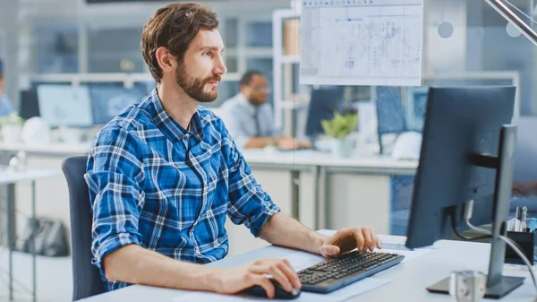 Na Instalação de Engenharia Industrial: Retrato do Bonito Engenheiro Inteligente Masculino Trabalhando em um Computador Desktop. No fundo Especialistas e técnicos que trabalham com rascunhos e desenhos — Fotografia de Stock