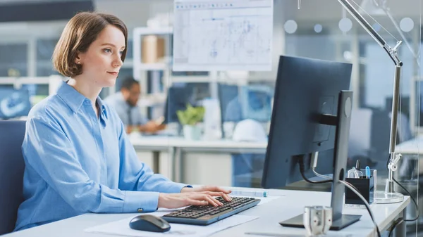 Na Instalação de Engenharia Industrial: Retrato da Engenheira Inteligente e Bela que Trabalha no Computador Desktop. No fundo Especialistas e técnicos que trabalham com rascunhos e desenhos — Fotografia de Stock