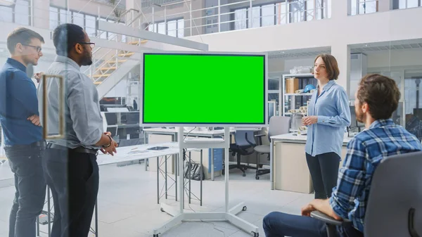 Στο In Industrial Design Facility Team of Engineers and Technicians έχουν μια συνάντηση, Γυναίκα Ειδικός Οδηγεί Ενημέρωση, Συζητήσεις και Χρήση Ψηφιακή Interactive Whiteboard με πράσινο Mock-up Screen — Φωτογραφία Αρχείου