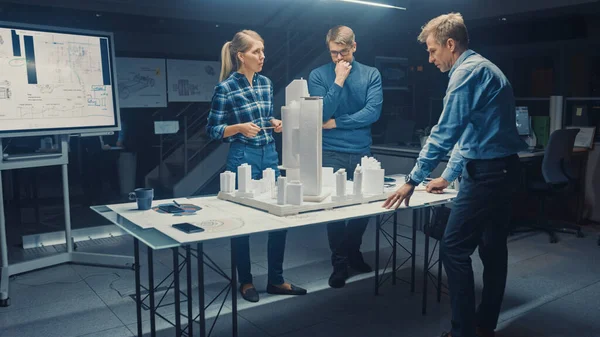 V Creative Architectural Agency dva profesionální designéři mluvit s hlavním projektovým inženýrem, Pracují na modelu městské čtvrti. Urban Planners Work on a Functional Building Model. — Stock fotografie