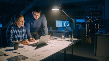 Endüstriyel Mühendislik Tesisi: Masaüstü Bilgisayarında Çalışan Kadın Mühendis, Proje Yöneticisi Görev ve Proje Detayları 'nın Yanında Duruyor ve Açıklıyor. Motor Prototipi Üzerinde Geç Çalışma