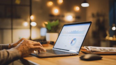 Erkek Uzmanların Elleri Üzerine Yakın Çekim Dizüstü Bilgisayar, Ekran Çeşitli Veri ve İstatistikleri Gösteriyor. Stylish Stüdyo Ofisinde Arka planda Akşam