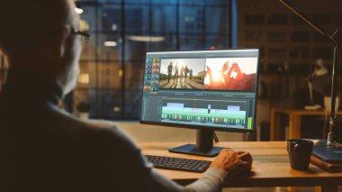 Omuz Fotoğrafı: Profesyonel Ortaçağ Videografisi, Masaüstü Bilgisayarında Çalışıyor, Video Montaj Yapıyor, Video Düzenleme Yazılımını Kullanıyor. Akşamları Modern Video Geliştiriciler Ofisi