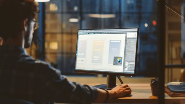 Genç Uygulama Geliştiricisinin Omuz Çekimi Masaüstü Bilgisayarını kullanarak, Yeni Cep Telefonu Uygulama Tasarımı, Yazılım UI Geliştirme Omuzları üzerinde. Şehir Penceresi Görünümlü Modern Ofis Stüdyosunda Akşam