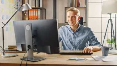 Moda Ofisi 'ndeki Masasında Oturan Yaratıcı Girişimci Masaüstü Bilgisayarı. Yakışıklı Kafkas Adam Bilgisayar Kullanıyor. Modern Minimalizm Tasarımı ile Arka plan Moda Ofis Stüdyosunda