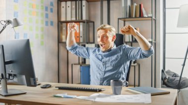 Moda Ofisi 'ndeki Bilgisayar Masasında Oturan Yaratıcı ve Çıkan Girişimci, Önemli Proje Başarı Hakkında İyi Haberler Aldı, Kazanan Jestler ve Mutlu Alkışlarla Kutladı.