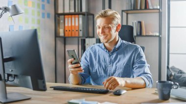 Moda Ofisi 'nde Masasında Oturan Yaratıcı Girişimci, Smartphone, Sosyal Medya Uygulamaları, E- posta Ortakları, Mesajlaşma Arkadaşları Kullanıyor ve Kullanıyor