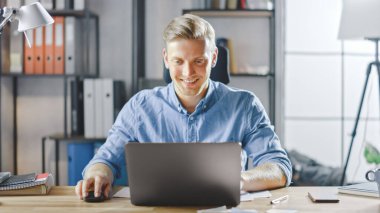 Ofisteki masasında oturan yakışıklı sarışın iş adamı dizüstü bilgisayarda çalışıyor. Yazılım Unicorn Startup Project üzerinde çalışan yaratıcı girişimci. Üniversite için Öğrenci Yazma Kağıdı