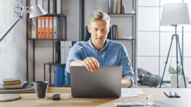 Çalışma masasında oturan yaratıcı girişimci stil ofisindeki bir dizüstü bilgisayarda çalışır, sosyal medya uygulamaları için yazılım kullanır, e-posta şirketleri, haberleri okur, internete göz atar.