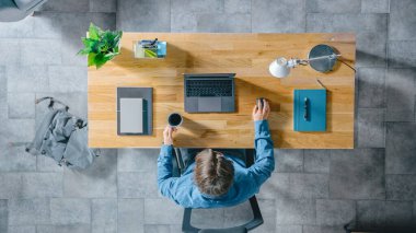 Top View shot: İşadamı İçişleri Bakanlığındaki bir dizüstü bilgisayarla Ahşap Masa 'da oturuyor. Kahve içer, daktilo yazar, e-posta yazar, internette sörf yapar, yazılım tasarlar, online alışveriş yapar.