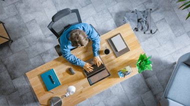 Top View shot: İşadamı İçişleri Bakanlığındaki bir dizüstü bilgisayarla Ahşap Masa 'da oturuyor. İnternette Yazar, Yazar, Sörf yapar, Yazılım yaratır ve Tasarlar, Çevrimiçi Alışveriş