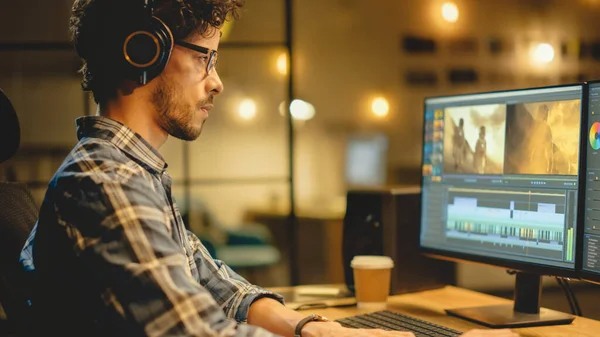 Evening in Creative Office: Professional Videographer Audio Engineer Wearing Headphone Works on Desktop Computer, Screen Shows: Footage Montage, Using Video Editing Software, Syncing Audio Track — 스톡 사진