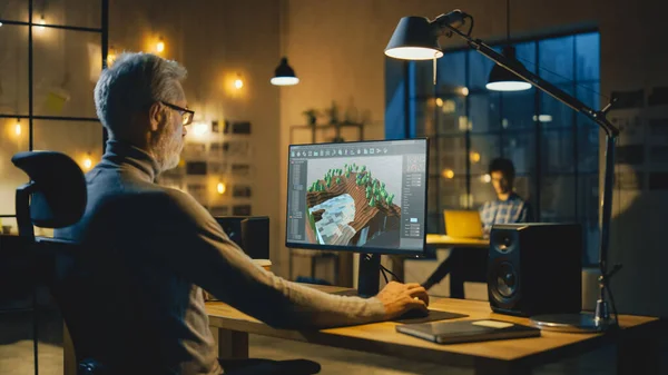 Am Abend arbeitet der kreative mittelalterliche Videospielentwickler an einem Desktop-Computer mit 3D-Videogame-Level-Design. Berufstätiger Büroangestellter arbeitet spät abends in seinem Atelier — Stockfoto