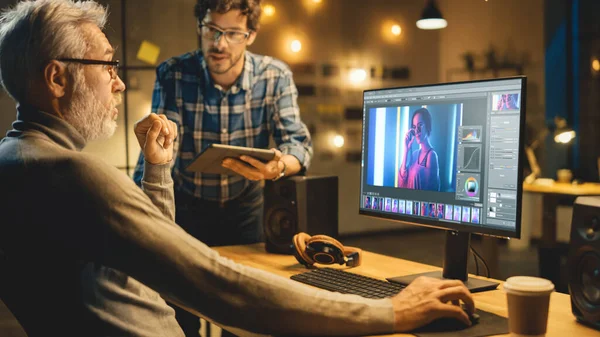 The Evening Creative Ortaçağ Fotoğraf Editörü Masaüstü Bilgisayar Görüntü Düzenleme Yazılımını Kullanıyor, Tablet Bilgisayar kullanan Genç Uzmanla Sohbet Ediyor. Akşamları Şık Ofis