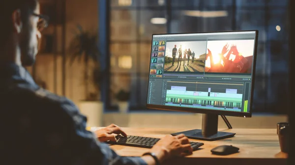 Over th Shoulder Shot: Jonge professionele Videograaf werkt op Desktop Computer, Doen Beelden Montage, Met behulp van Video Editing Software. Modern Video Developers Office in de avond — Stockfoto