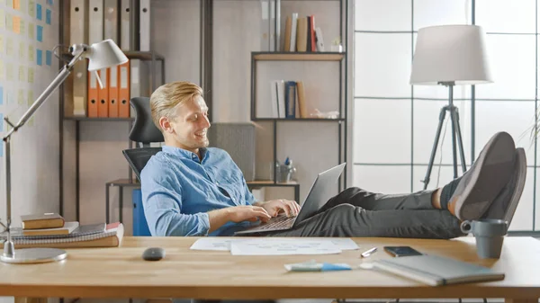 Przystojny młody przedsiębiorca pracuje na laptopie z nogami na biurku. Projektant używa notebooka do tworzenia oprogramowania Unicorn Startup. Papier do pisania Chill Student dla Uniwersytetu — Zdjęcie stockowe