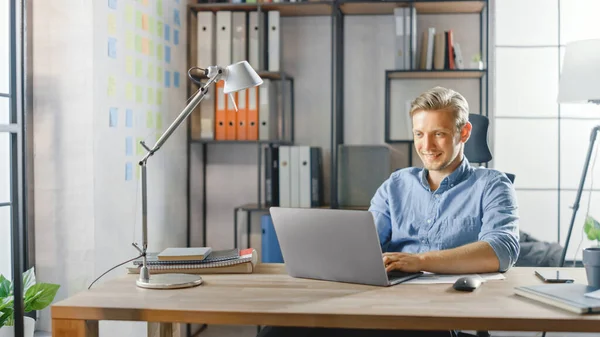 Empresario creativo sentado en su escritorio funciona en una computadora portátil en la oficina con estilo, utiliza software para aplicaciones de redes sociales, Emailing Business Associates, Reading News, Navegar por Internet — Foto de Stock