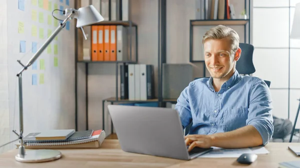 Creative Entrepreneur Sitting at His Desk Works on a Laptop in the Stylish Office, Χρησιμοποιεί το Σημειωματάριο για τα Social Media Apps, Emailing Business Associates, Reading News, Περιήγηση στο Διαδίκτυο — Φωτογραφία Αρχείου