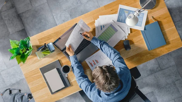 Ofisteki Masasında Oturan İşadamı Dizüstü bilgisayar kullanıyor, Şirket Strateji Belgeleri, Çizelgeler, Çizimler ve İstatistikler ile çalışıyor. Üst Görünüm Görüntüsü