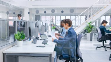 Modern Ofis 'te: Çeşitli Menajerler ve Uzmanlar Bilgisayar Üzerinde Çalışıyor, Meslektaşlarla Tartışıyor ve Telefonda Çalışıyor. Açık Ofiste Genç ve Motivasyonlu İş Adamları.