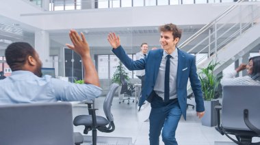 Genç Mutlu İş Yöneticisi Takım Giyiyor, Kravat Dansı Yapıyor ve Ofiste Çak Beşlik Yapıyor. Başarımızı kutluyoruz. Modern Açık Ofiste Çeşitli ve Motivasyonlu İş Adamları Bilgisayarlar Üzerinde Çalışıyor.