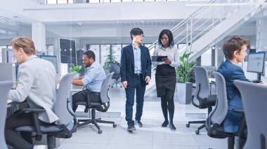 Genç Erkek ve Bayan İş Arkadaşı Ofiste Tablet Bilgisayar ve Tartışma Çalışması Tutuyor. Modern Açık Ofisteki Motivasyonlu Çeşitli İş Yöneticileri. 