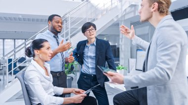 Çeşitli İşletme Yöneticileri ve Uzmanlardan oluşan Ekip Kağıt ve Tablet Bilgisayar Grafikleri üzerine Sohbet ve Tartışma. Modern Açık Ofiste Genç ve Motivasyonlu İş İnsanları.