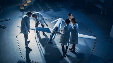 Uzay Mühendisleri Toplantısı İnsansız Hava Aracı Drone Prototipi üzerinde çalışıyor. Beyaz önlüklü havacılık bilimcileri konuşuyor. Gözetleme ya da Askeri Uçak Endüstriyel Laboratuvarı. Yükseltilmiş Vuruş