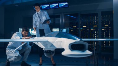 İnsansız Hava Aracı Drone Prototipi üzerinde çalışan Uzay Mühendisleri Toplantısı. Beyaz önlüklü havacılık bilimcileri konuşuyor. Endüstriyel Laboratuvarda Ticari Hava Gözetleme Uçağı