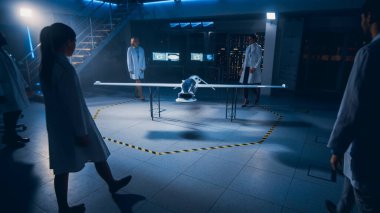 Uzay Mühendisleri Toplantısı İnsansız Hava Aracı Drone Prototipi üzerinde çalışıyor. Beyaz önlüklü havacılık bilimcileri konuşuyor. Gözetleme ya da Askeri Uçak Endüstriyel Laboratuvarı.