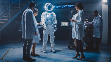 Çeşitli Uzay Mühendisleri Ekibi Galaksi Keşfi ve Seyahat İçin Yeni Uzay Giysileri Tasarladı. Beyaz önlük giyen bir grup bilim adamı tartışır, bilgisayar kullanır. Astronot Kıyafeti Yapılıyor